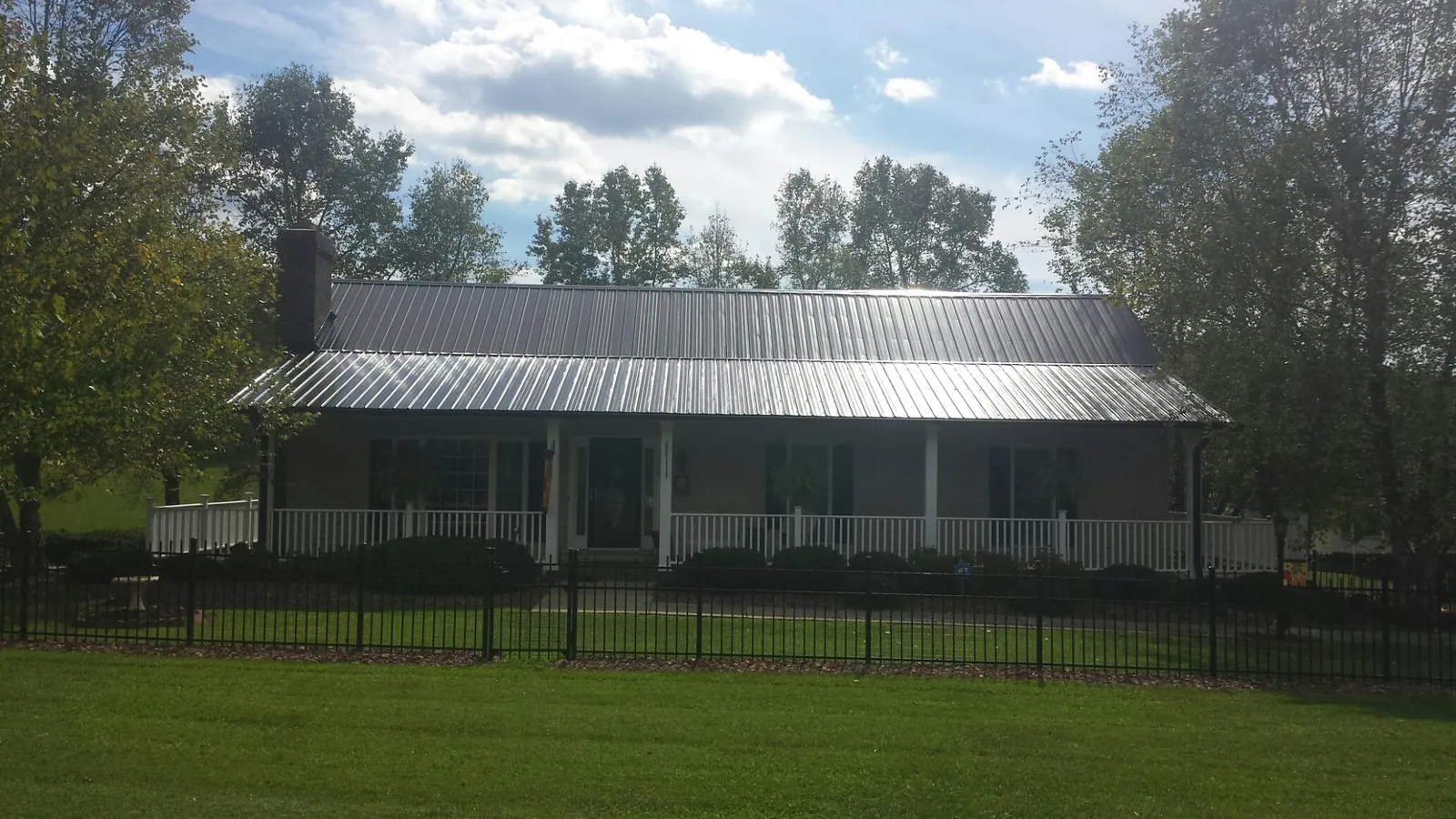 Gray metal roof on a brick ranch with a full width front porch — Gutter Guard Installation work by our crew in Pelham