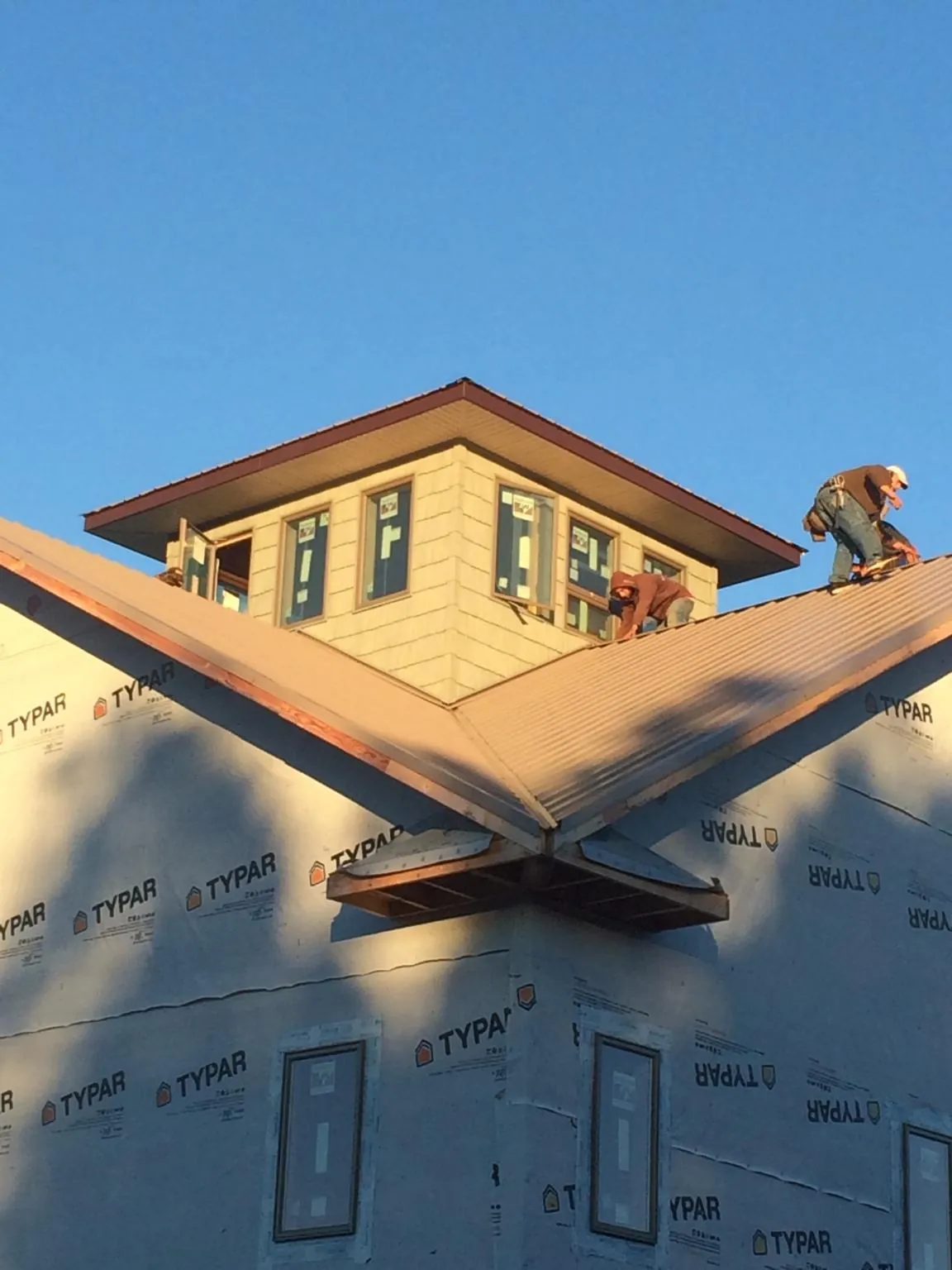 Roofers working around a rooftop cupola on a new metal roof at sunset — Roof Waterproofing in Pelham by Roofing Brothers